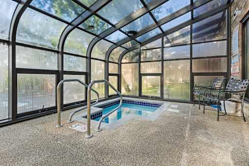 a indoor hot tub in a greenhouse with chairs and a wall of windows