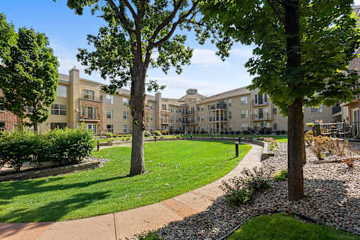 a park with trees and grass in front of an apartment building
