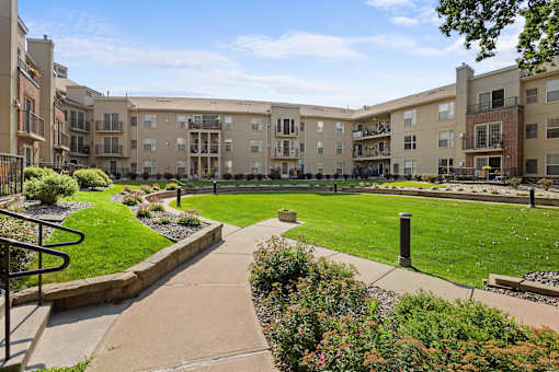 A sunny day at a well-maintained apartment complex with a green lawn and walking paths.