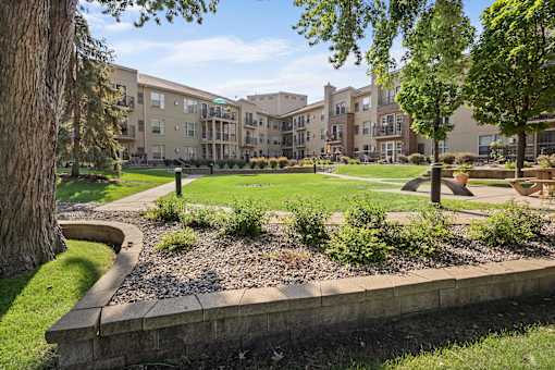 a courtyard with trees and grass in front of an apartment building