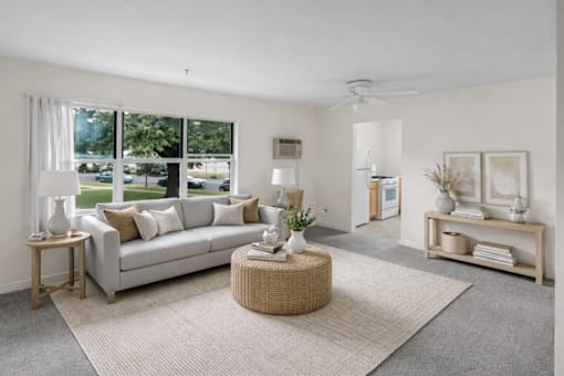 A living room with a grey couch, a round wicker table, and a grey rug.