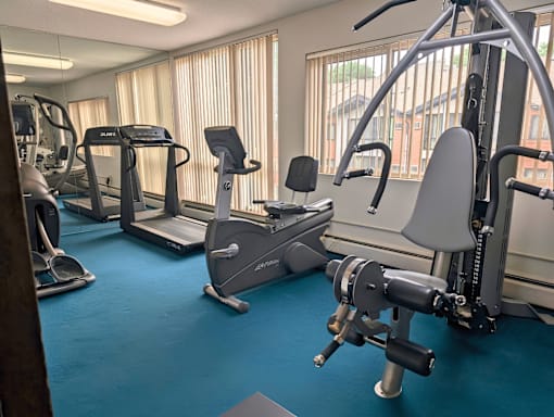 A gym with a variety of equipment including treadmills, stationary bikes, and weight machines.