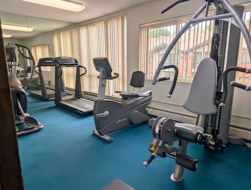 A gym with a variety of equipment including treadmills, elliptical machines, and weight machines.