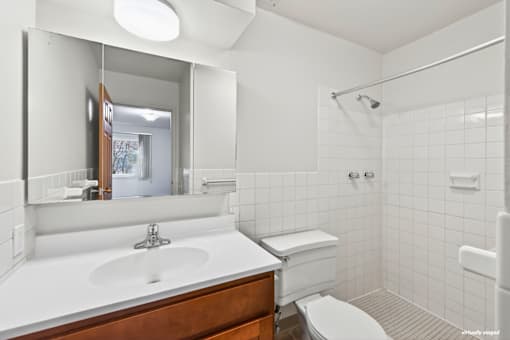 A white bathroom with a sink, toilet and shower.