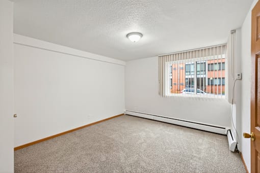 A room with a window and a carpeted floor.