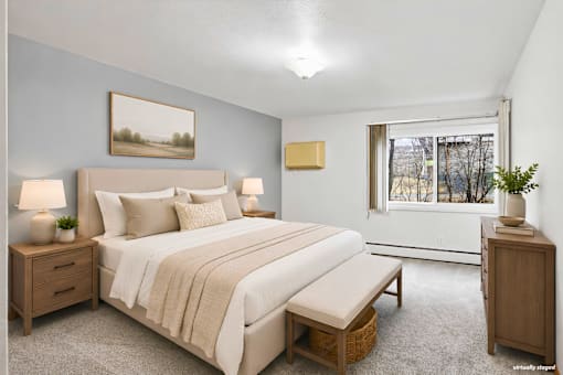 A bedroom with a large bed, nightstands, and a window.