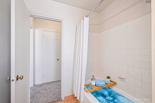 A bathroom with a white tub and a white shower curtain.