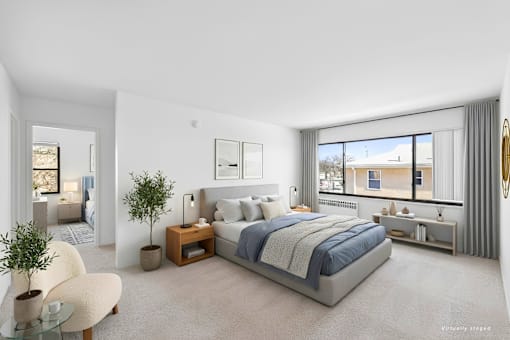 A bedroom with a large bed, a chair, and a plant.