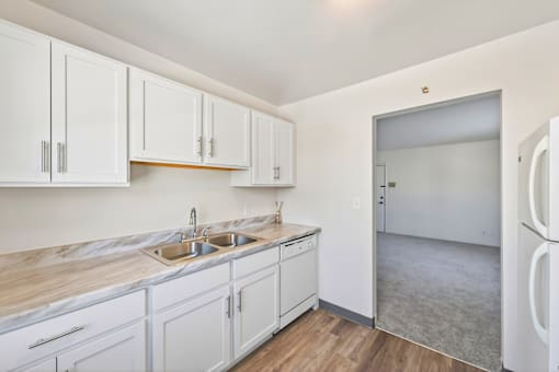 A kitchen with white cabinets and a marble countertop.
