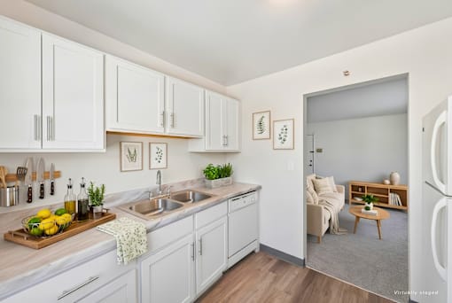 A kitchen with white cabinets and a wooden cutting board with lemons and herbs on it.