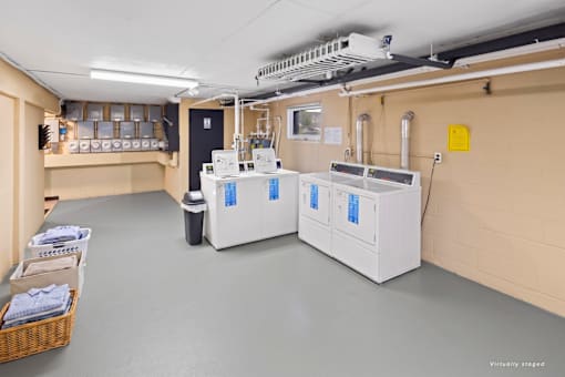 A room with two large white machines and a basket of towels on the left.