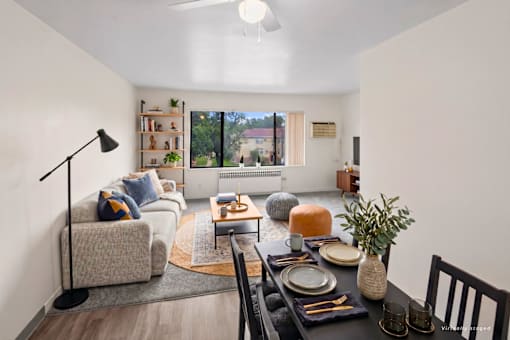 A well-lit living room with a dining table set for two.