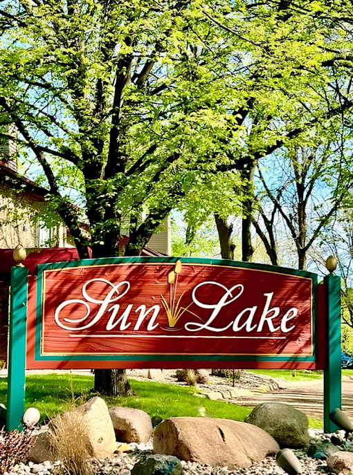 A sign that says Sun Lake in front of some trees.
