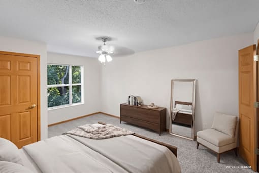 A bedroom with a bed, dresser, mirror, and chair.