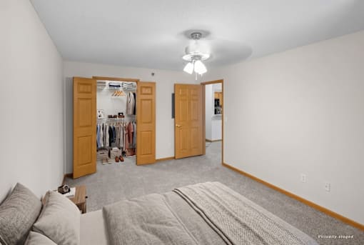A bedroom with a grey carpet and two open doors.