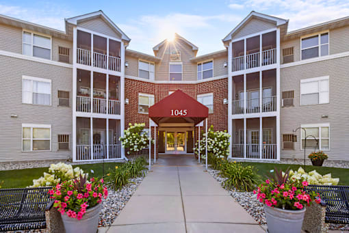 The image shows a beautiful day at the entrance of apartment building 1045 with a clear blue sky and sunlight shining through the windows.