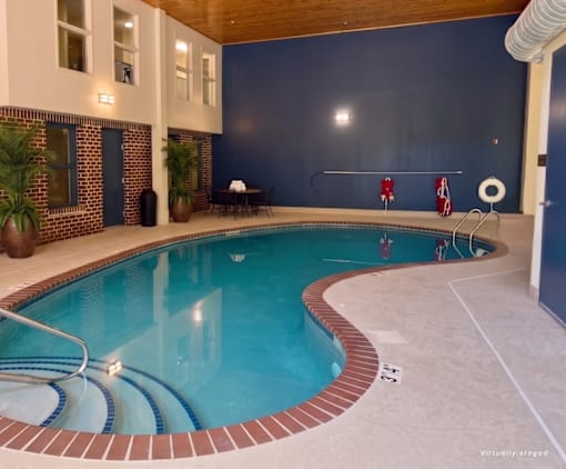 A swimming pool inside a house with a blue wall.