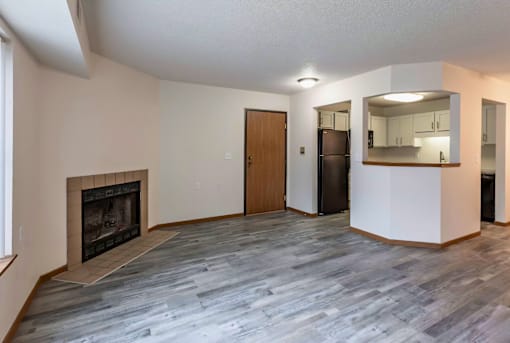 A living room with a fireplace and a kitchen area in the background.