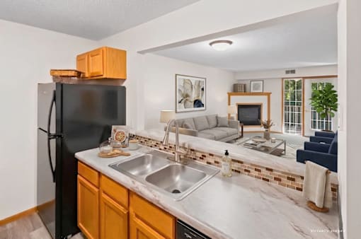 A kitchen with a black refrigerator and a marble countertop.