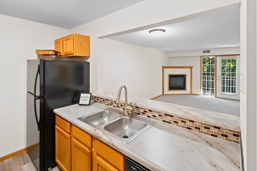 A kitchen with a black fridge and a marble countertop.