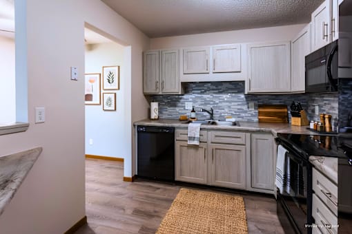A kitchen with a black fridge and stove top oven.