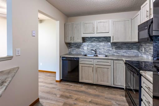 A kitchen with a black fridge, black countertops, and a black stove.