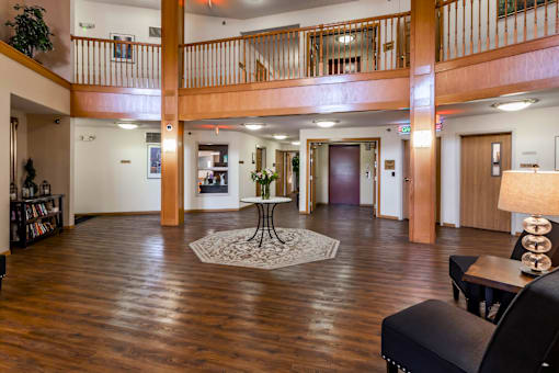 A large open space with a table and chairs in the foreground and a balcony in the background.