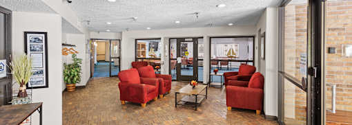 A living room with red chairs and a wooden floor.