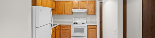 A white refrigerator is in a kitchen with wooden cabinets.