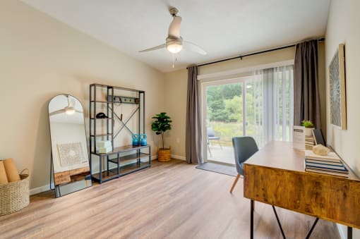 a living room with a desk and a sliding glass door