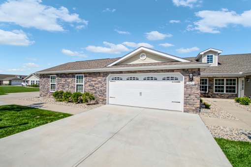 A house with a white garage door and a stone wall.
