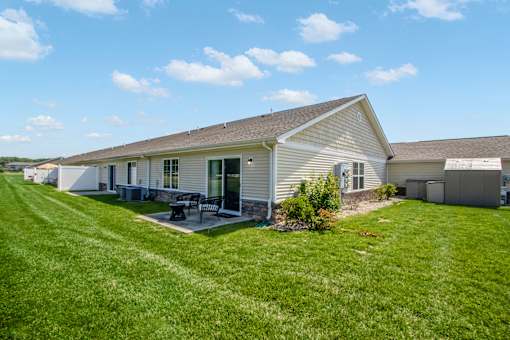 A house with a green lawn and a picnic table in front.