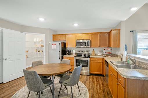 A kitchen with a table and chairs in front of it.