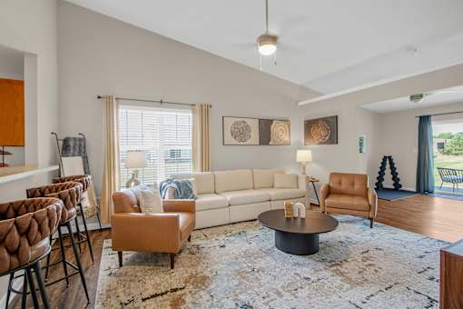 A living room with a white couch, brown chairs, and a rug.