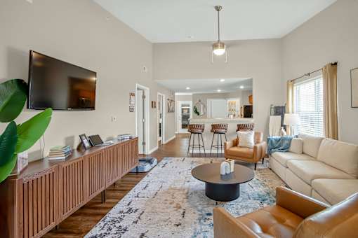 A living room with a large couch, a coffee table, and a television mounted on the wall.