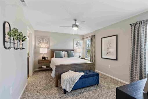 A bedroom with a bed, nightstand, and a plant on the wall.
