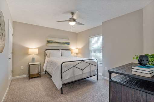 A bedroom with a bed, nightstands, and a ceiling fan.