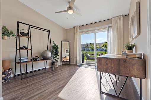 A room with a wooden floor and a sliding glass door leading to a balcony.