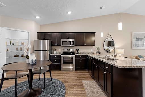 A modern kitchen with dark brown cabinets and stainless steel appliances.