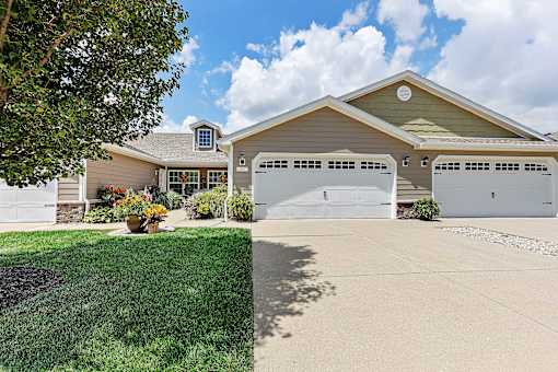A house with a garage and a tree in front.