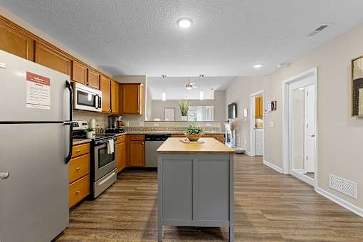 A kitchen with a refrigerator, microwave, oven, and sink.