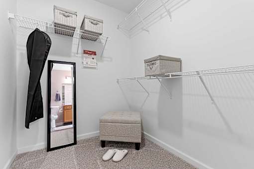 A white closet with a mirror, a bench, and a pair of slippers.