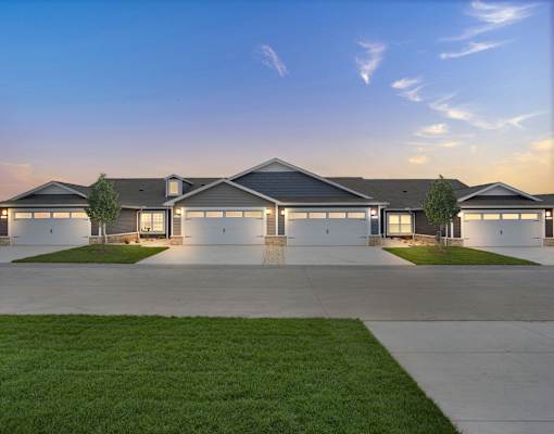 A modern house with a grey roof and white walls is shown with a clear blue sky in the background.