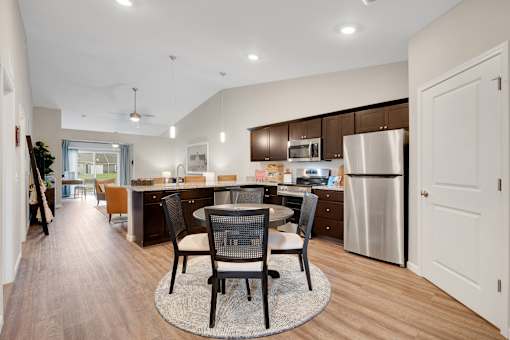A modern kitchen with a dining table and chairs in the middle.