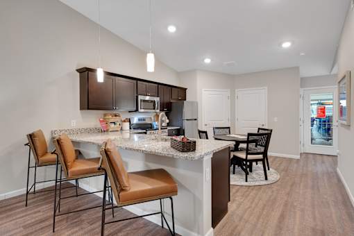 A kitchen with brown chairs and a white counter.