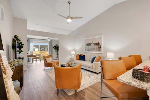 A living room with a white couch and orange chairs.