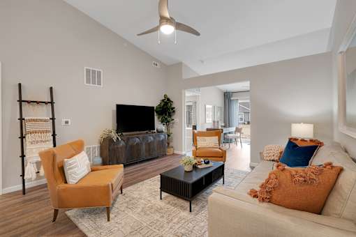 A living room with a brown chair, a white couch, and a black coffee table.
