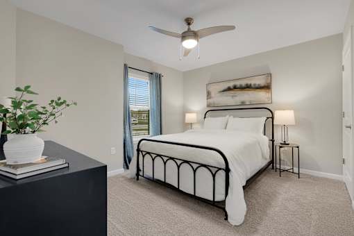 A bedroom with a bed, nightstands, and a ceiling fan.