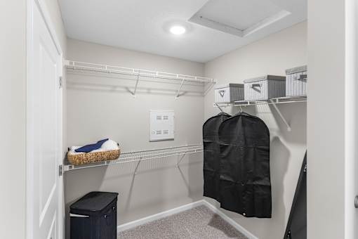 A walk-in closet with a black coat hanging on a hanger.