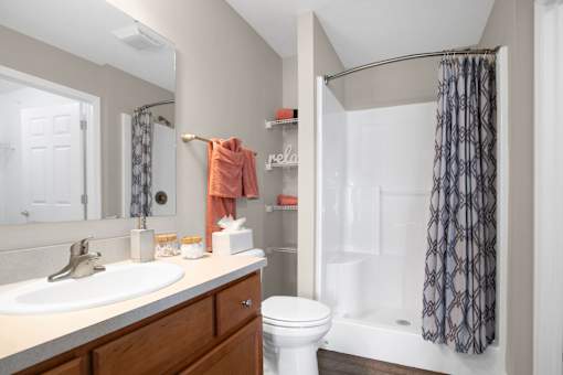 A bathroom with a white toilet, sink, and shower.